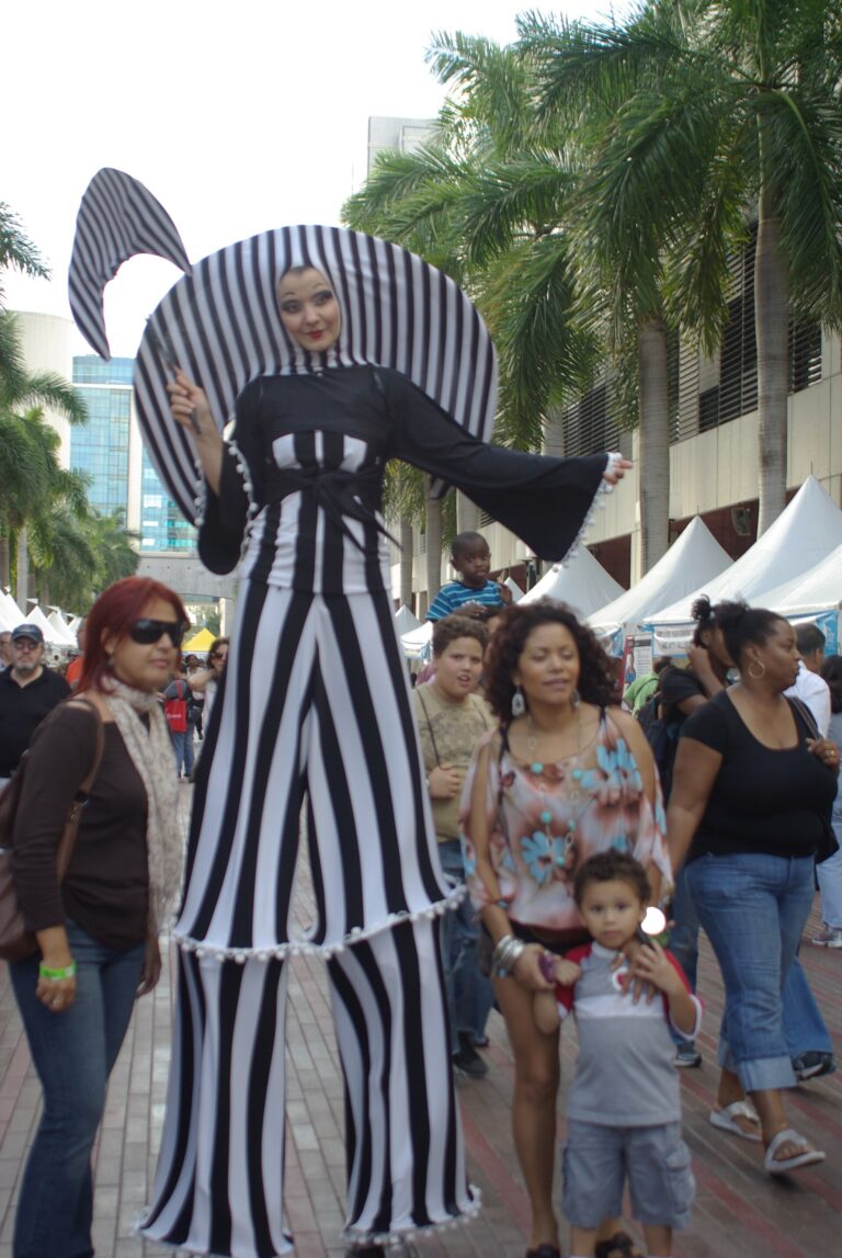 Miami Book Fair archival context: a striped-costume stilt performer among outdoor attendees in 2011, not the 2026 event